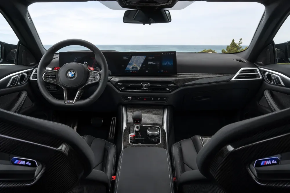 Wnętrze BMW M4 Competition — widok deski rozdzielczej i foteli przednich